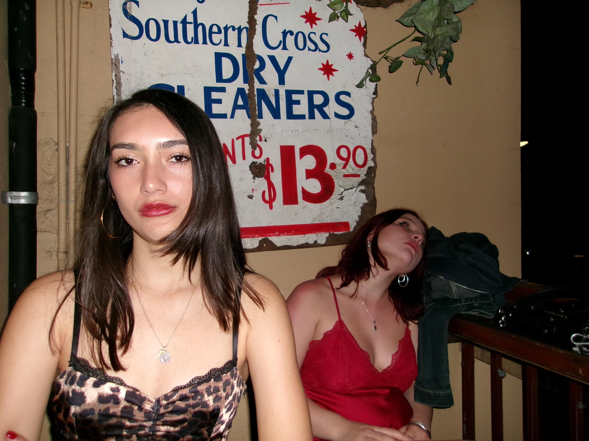 Two people posing beside a vintage dry-cleaning sign.
