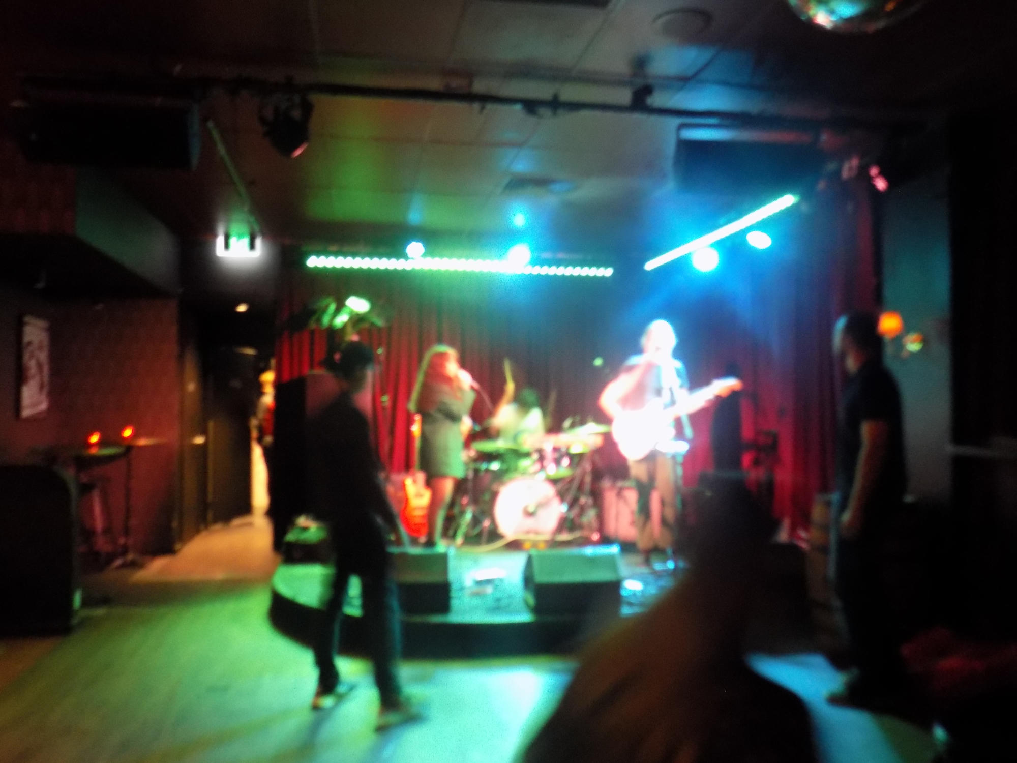 A band performing on a small stage under colorful lights.