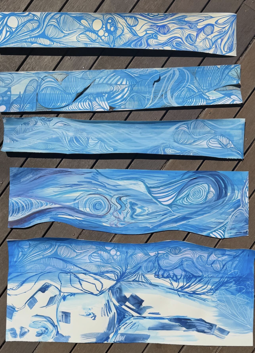 Five long blue abstract artworks arranged vertically on a wooden deck.